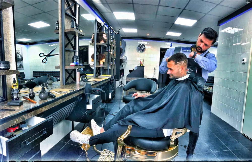 Interieur van Kapsalon King Style in Kerkrade — de kapper aan het werk aan de kappersstoel