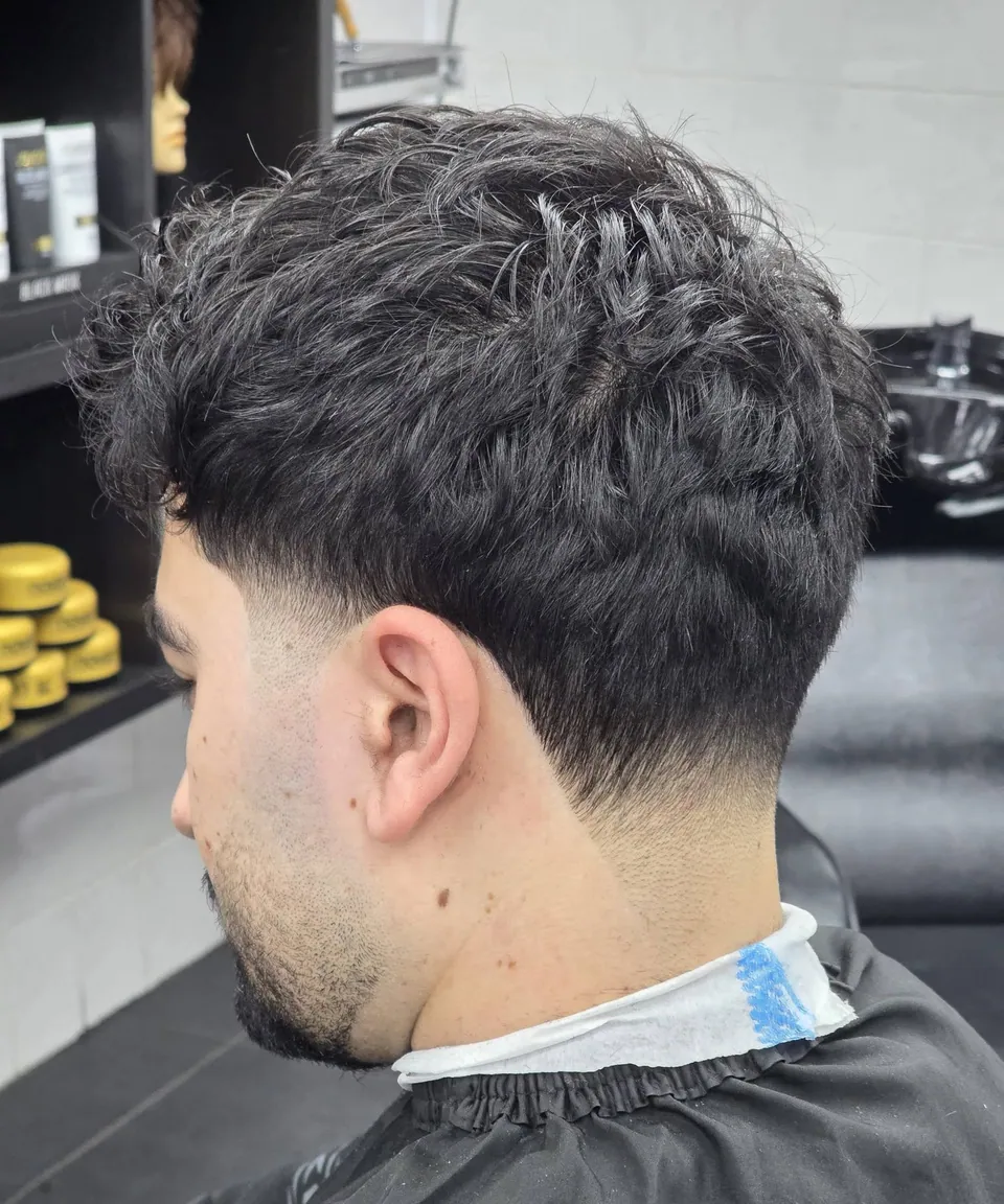 Heren coupe met textuur bovenop en lage taper fade, zij-achteraanzicht